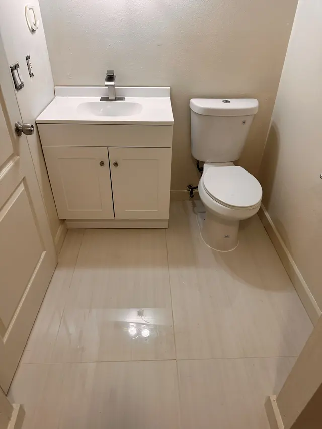 Finished bathroom with a white vanity, a toilet and large format tile flooring