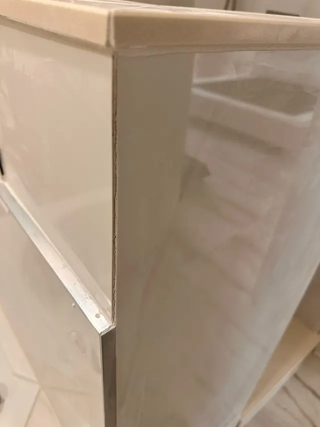 Close up of a finished shower surround with white tile and a clean caulk line