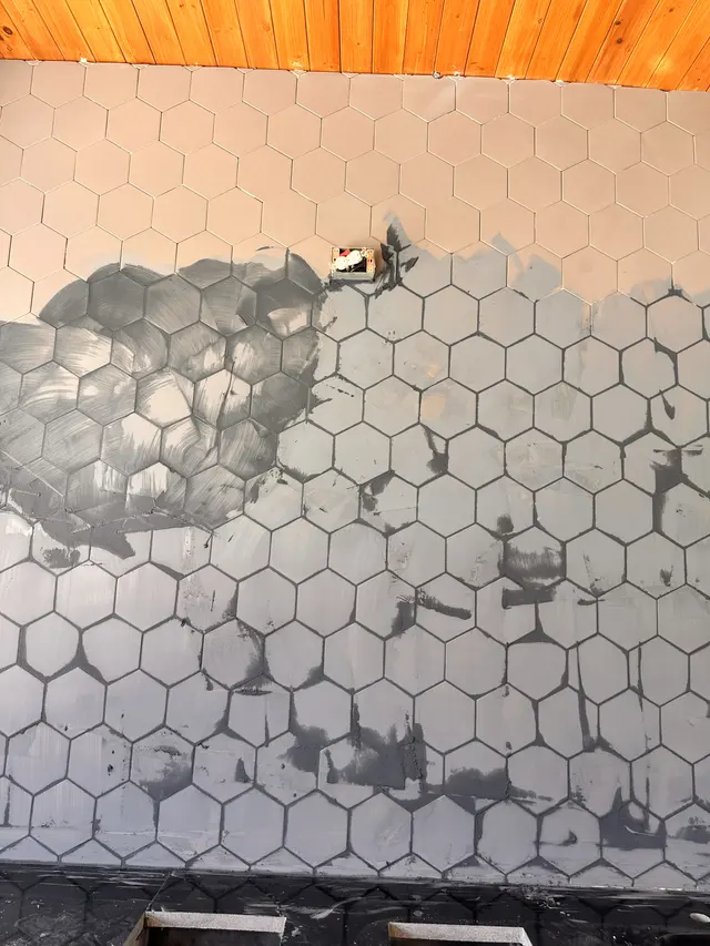 Hexagon tile going up on a wall, half set, with the substrate still visible
