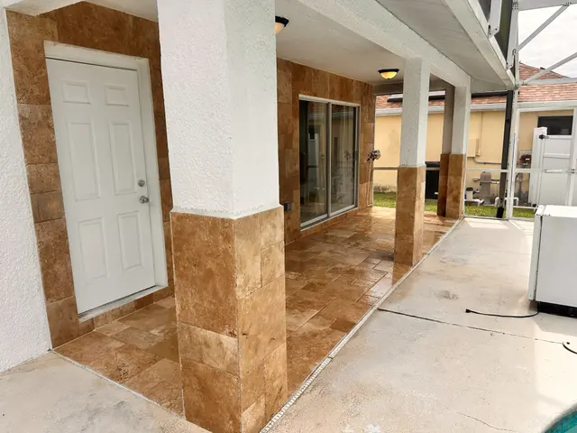 Covered entry with travertine flooring and stone wrapped columns
