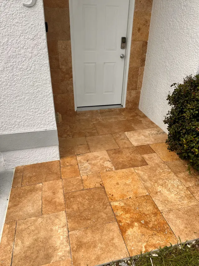 Front entry finished in travertine pavers next to a white door