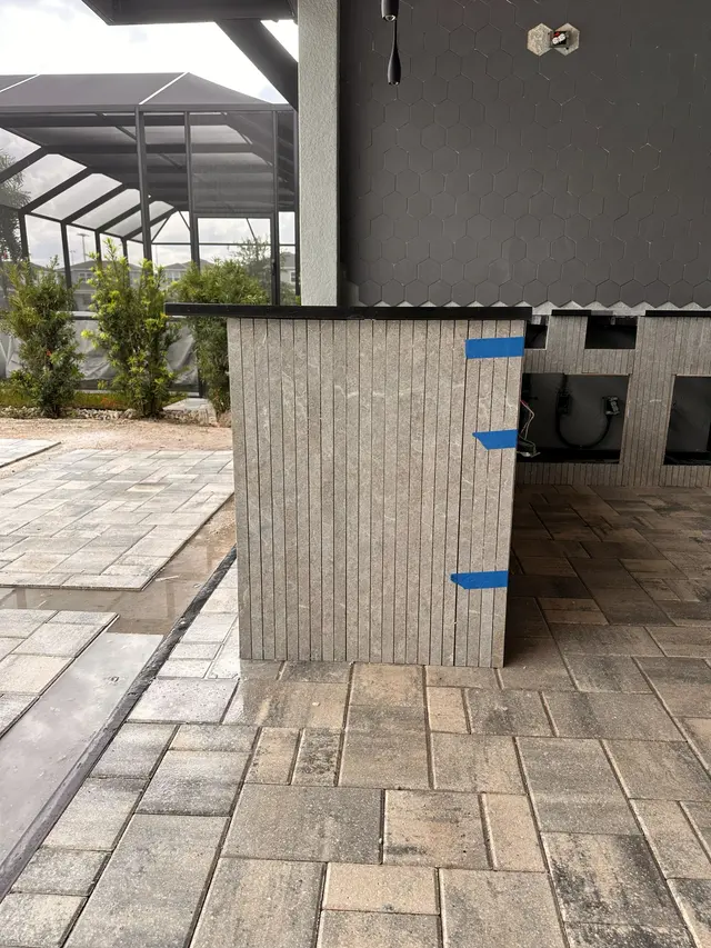 Outdoor kitchen structure under construction with the paver patio already laid