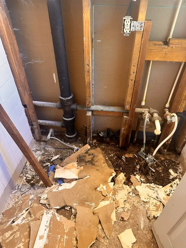 Bathroom stripped back during demolition, with drain lines and framing exposed