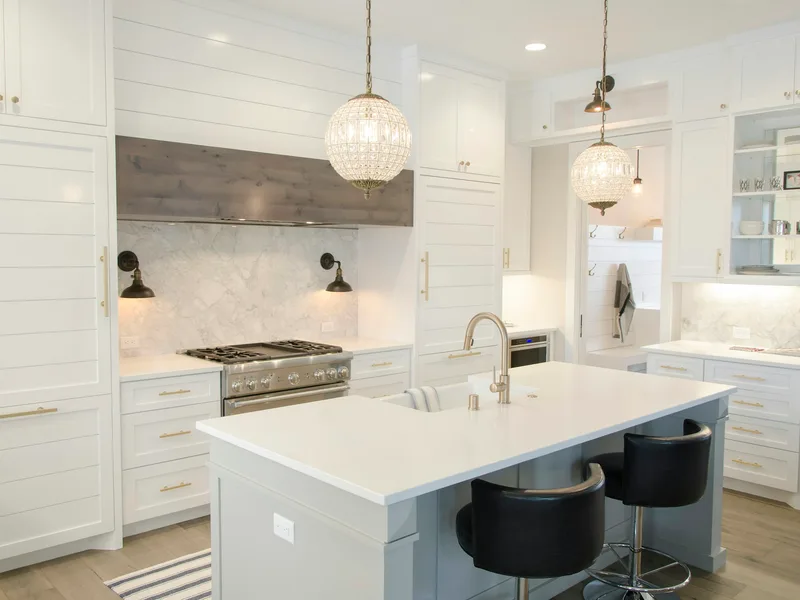 Remodeled kitchen with white cabinets, a stone island, a pro range and pendant lighting