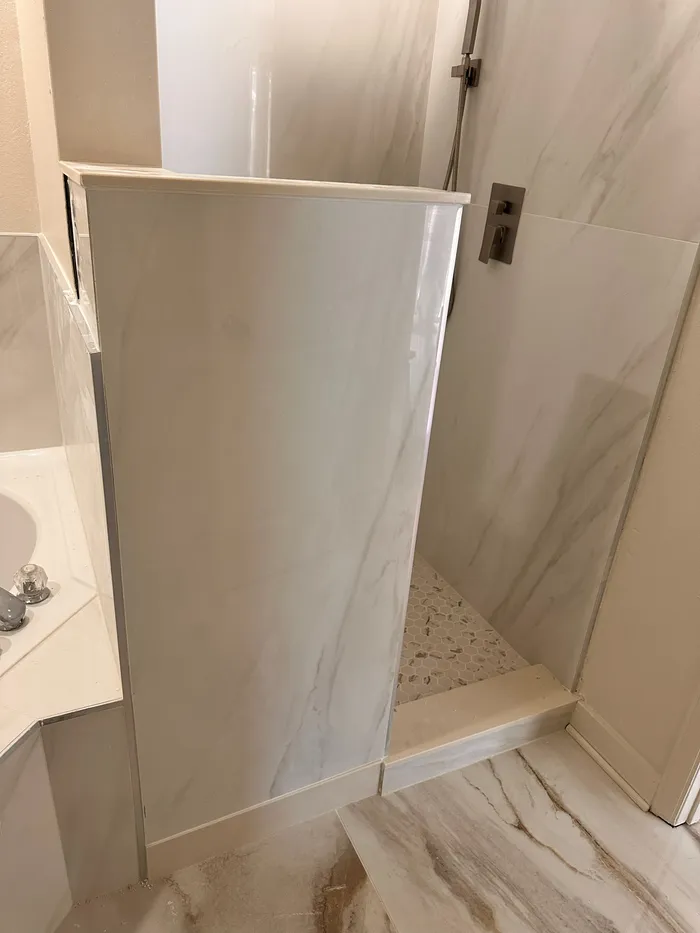 Finished walk in shower with a glass panel and light tile walls